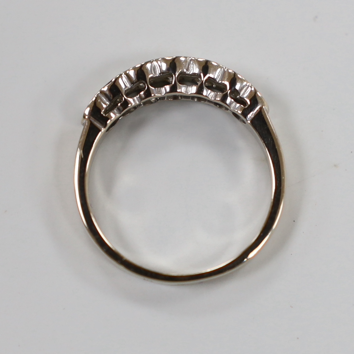 A modern white metal and graduated seven stone diamond set half hoop ring, size L, gross weight 3.2 grams.